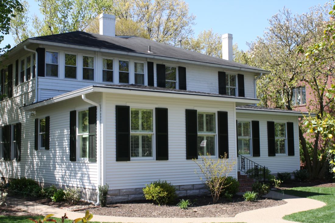 White two-story home with black shutters after an addition